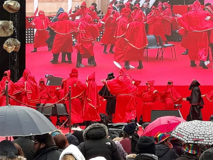 I Domini di Lavello, in mantella rossa e cappuccio, radunati davanti a un palco durante la festa