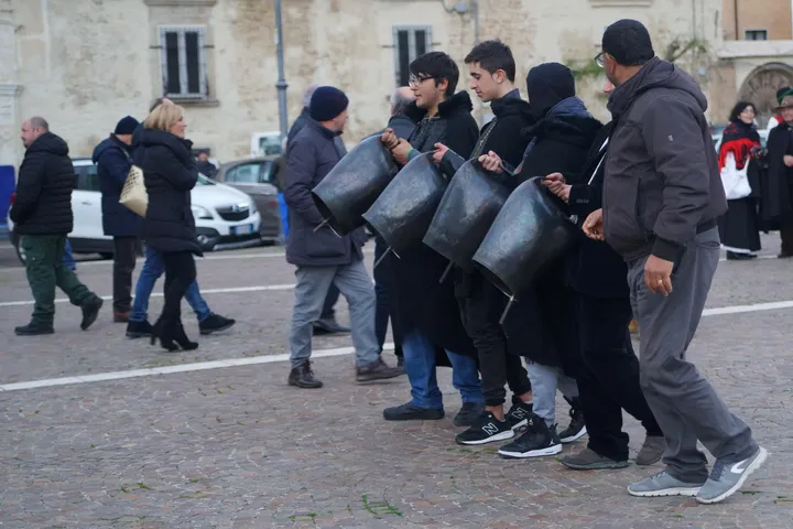 Un gruppo di scampanatori percorre una via di San Mauro Forte reggendo grandi campanacci di bronzo