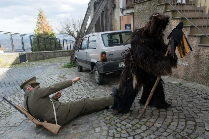 L’Urs, l’orso dal folto manto scuro, sovrasta un figurante disteso a terra in una via di Teana